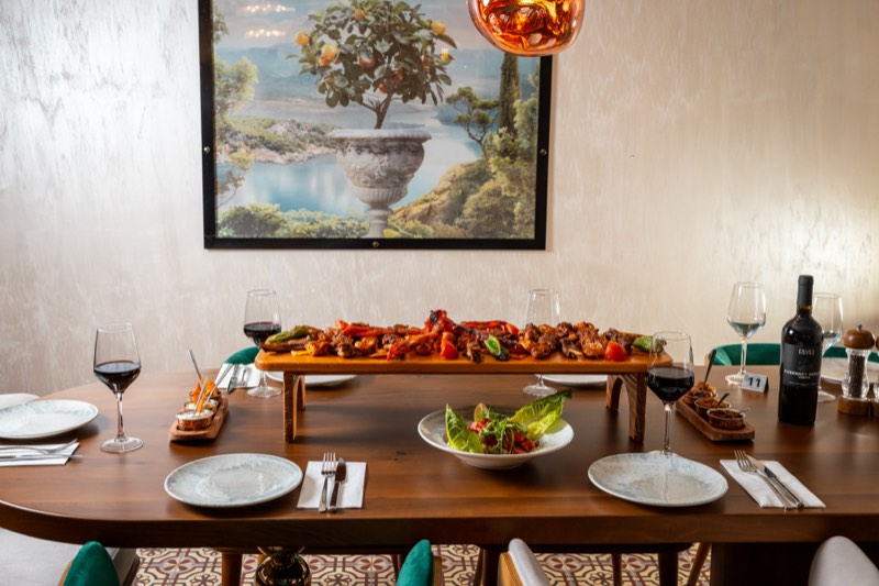 A long table laid for a feast beneath the mural